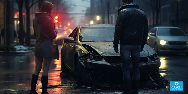 A pedestrian and a motorist standing on a street with a car accident in the background
