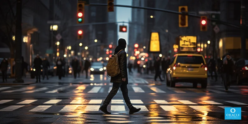 A pedestrian crossing a street with a marked crosswalk and traffic lights in the background