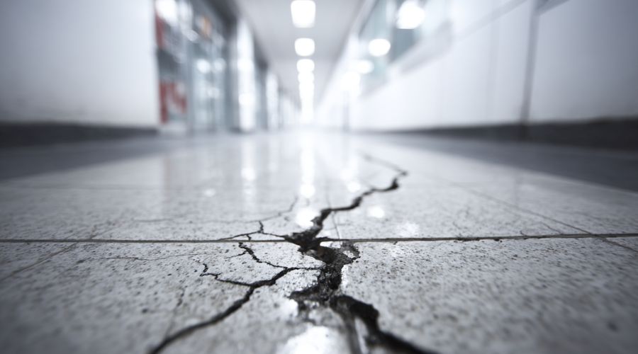 A cracked tile inside a business hallway. The defect is clearly visible and poorly maintained. No people present.