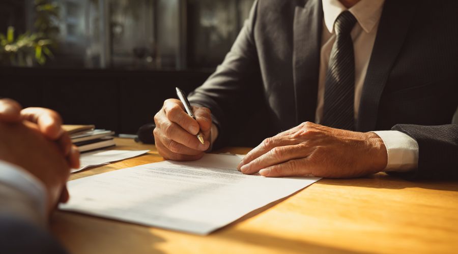A professional attorney reviewing accident documents with a client at a desk, neutral office setting, paperwork visible, calm and serious tone, natural lighting, authentic legal consultation