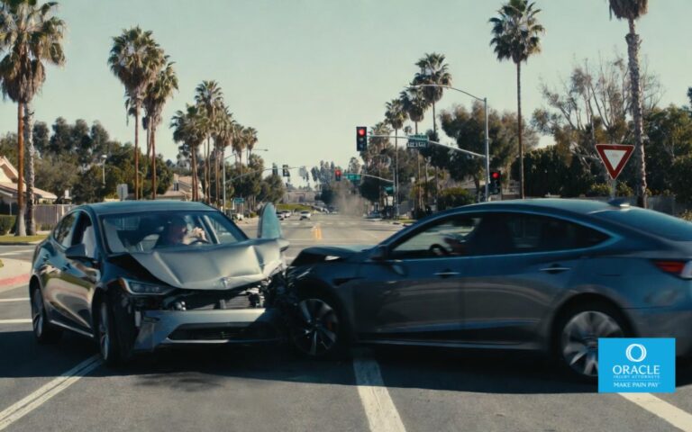7,1s A realistic scene of a car accident at a suburban intersection in Yorba Linda, California, during daylight, featuring two modern vehicles involved in a minor collision, one attempting a left turn and the other going straight. Surroundings include palm trees, residential houses, traffic lights, and clear road markings. A slightly blurred motion effect suggests sudden impact, while a distracted driver holding a phone is visible inside one vehicle.