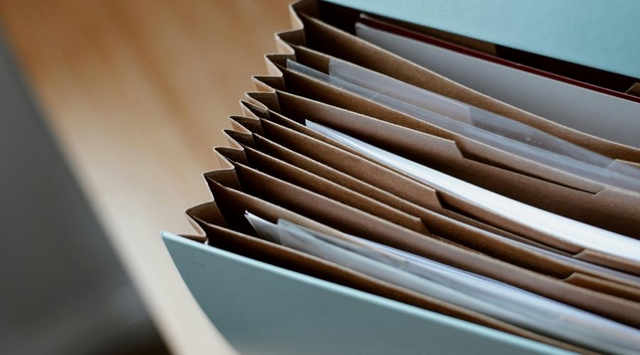 What Happens If You Are Injured in a Car Accident in Irvine? 2 A close-up image of organized legal documents stored in an accordion-style file folder. The paperwork appears neatly categorized, representing the documentation and evidence often collected after a car accident, such as medical records, police reports, and insurance paperwork.