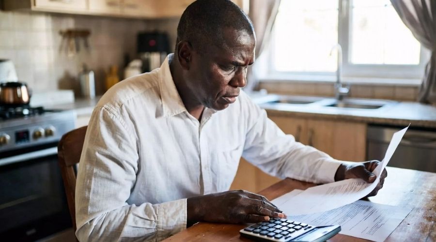 A claimant sitting at a kitchen table reviewing a settlement offer letter with a concerned expression, calculator and paperwork nearby, warm indoor lighting, intimate and realistic scene, focus on decision-making moment