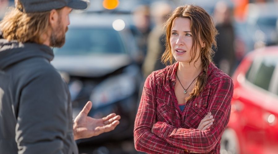 What Should You Do After a Hit-and-Run Accident in Riverside? 2 Two individuals talking near a roadside accident, one gesturing while explaining what they saw, both appearing serious and engaged, cars stopped nearby, natural candid moment