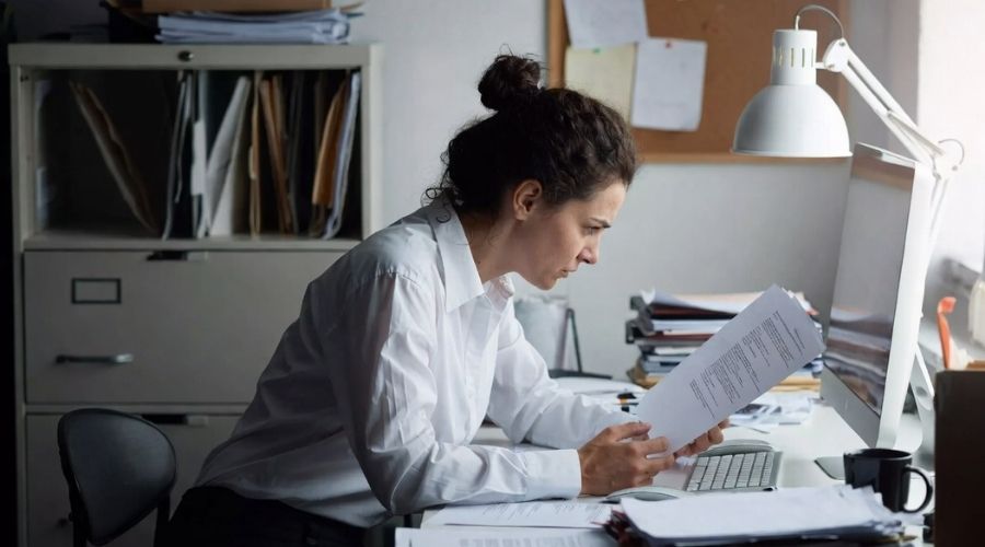 Compensación laboral en Anaheim: Lo que los empleados lesionados deben saber en 2026 3 Un trabajador frustrado mirando una carta de reclamación denegada mientras está sentado en un escritorio desordenado, iluminación ligeramente tenue para transmitir estrés, expresión emocional realista, entorno profesional, alto nivel de detalle.