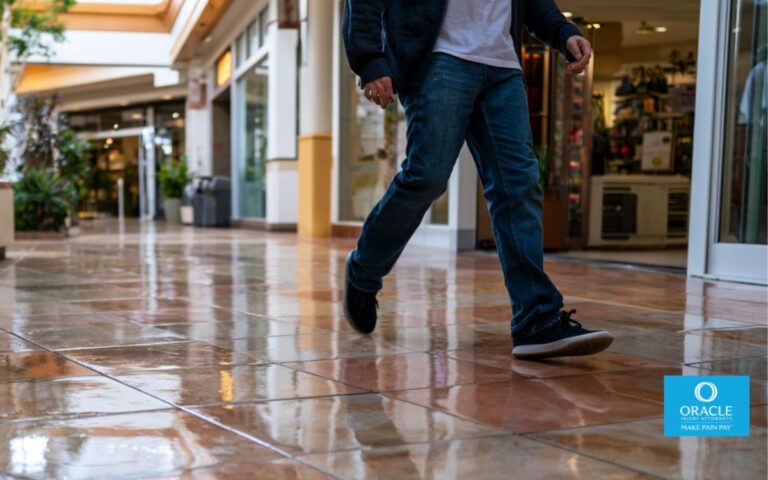 Murrieta shopping center walkway, wet floor hazard with subtle reflection, a person slipping mid-step, natural body movement, realistic lighting, modern California retail environment, clean composition, cinematic depth of field, ultra realistic, 35mm photography style