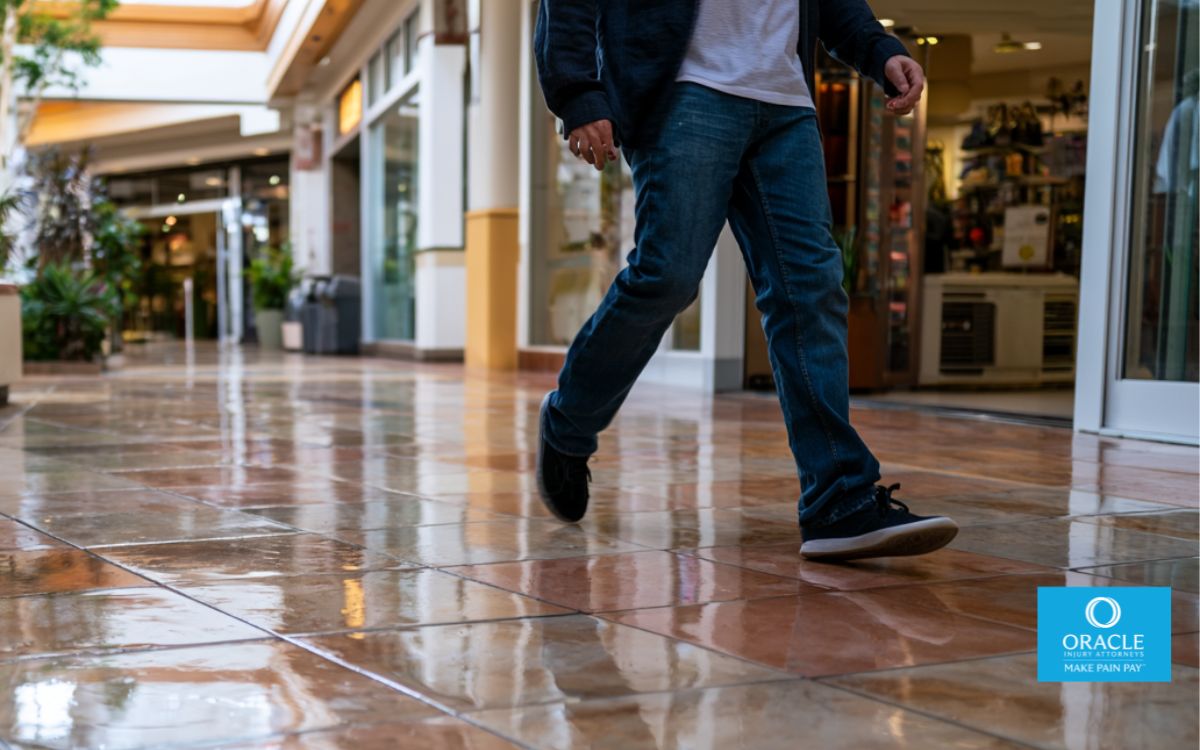 Pasillo del centro comercial Murrieta, peligro de suelo mojado con reflejo sutil, una persona resbalando a mitad de un paso, movimiento corporal natural, iluminación realista, entorno comercial moderno de California, composición limpia, profundidad de campo cinematográfica, ultrarrealista, estilo fotográfico de 35 mm