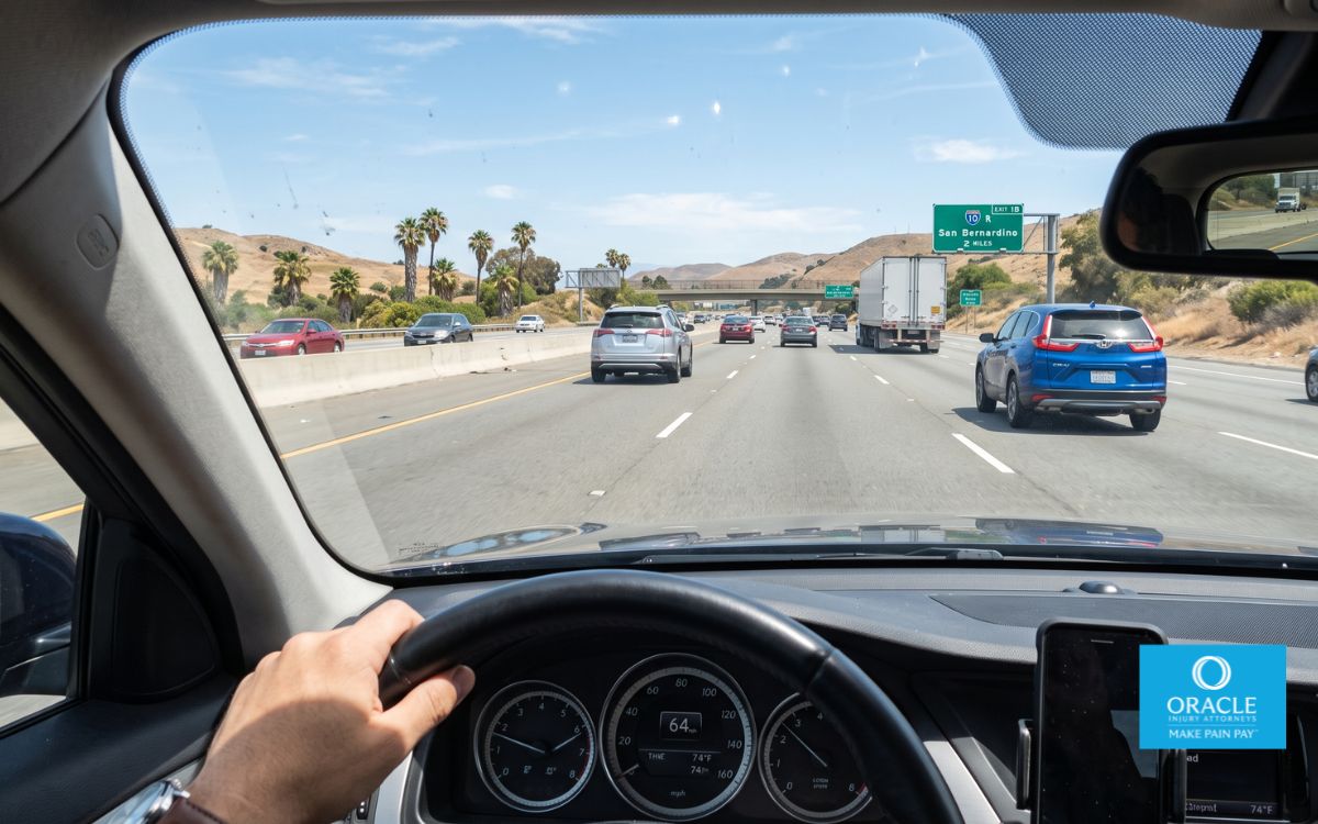Toma desde la perspectiva del conductor a través del parabrisas que muestra una distancia de seguridad amplia entre su coche y varios vehículos que circulan delante en una autopista de California, a plena luz del día. No se ven rostros.