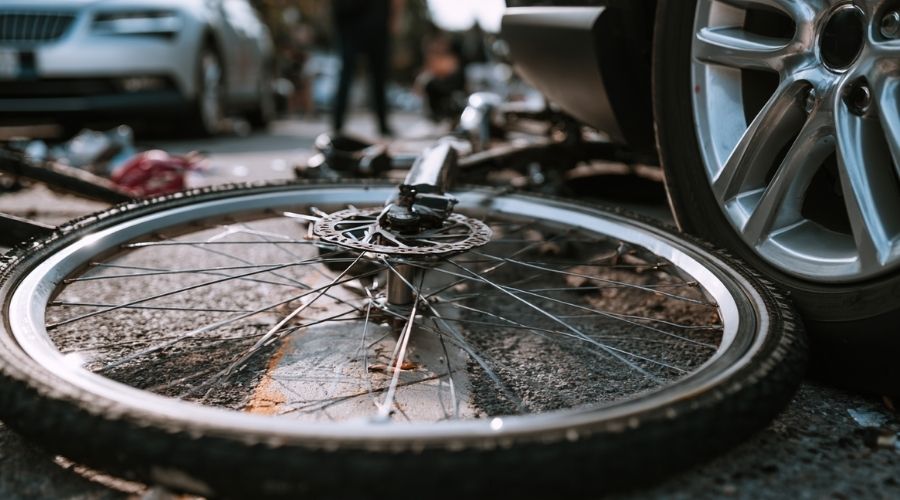 What Every Cyclist in Riverside County Should Know About Injury Claims 1 Close-up of a crumpled bicycle wheel on asphalt next to a car bumper after a collision, natural lighting, documentary-style photo.
