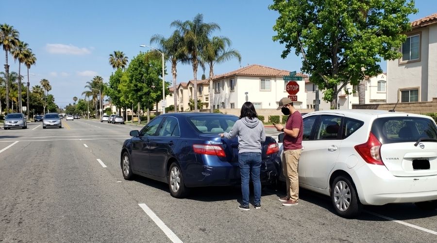 Escena de un choque por alcance entre dos autos detenidos muy cerca uno del otro en una calle residencial. Daños menores visibles. A plena luz del día. No se aprecian rostros claramente identificables ni lesiones graves.