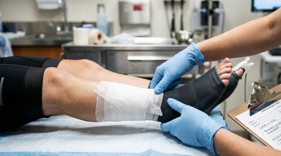 Bicycle Accident Claims: What Cyclists in California Need to Know About Compensation 1 A close-up of a cyclist's injury being assessed at a hospital or clinic — bandaged arm or leg resting on a medical table, only the injury and hands of a healthcare worker visible. No faces. Represents the medical documentation angle.