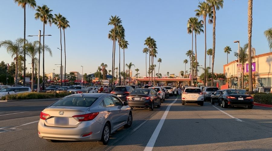 Buena Park Car Accident Claims: Steps to Protect Your Case 2 A busy entertainment venue parking lot entrance with a mix
of rental cars, rideshare vehicles (Lyft/Uber trade dress
blurred), and regular passenger vehicles queuing, daylight.
No faces clearly visible. Represents the tourist traffic
liability dynamic unique to Buena Park.