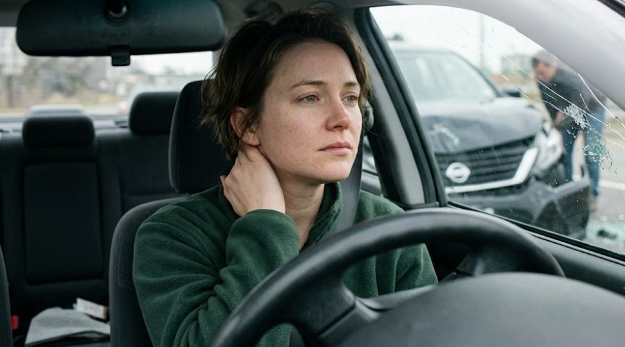 Whiplash After a Car Accident: Why Symptoms Can Take Days to Appear 1 Close-up portrait of an adult sitting in the driver's seat immediately after a minor car accident, relieved with no visible injuries, gently touching the back of their neck, damaged vehicle visible through the windshield, soft natural daylight, realistic skin texture, candid documentary photography, ultra detailed, 50mm lens, shallow depth of field, editorial style, no text