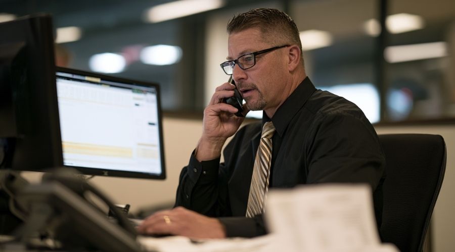 Insurance claims adjuster reviewing a claim while speaking with a claimant by phone.