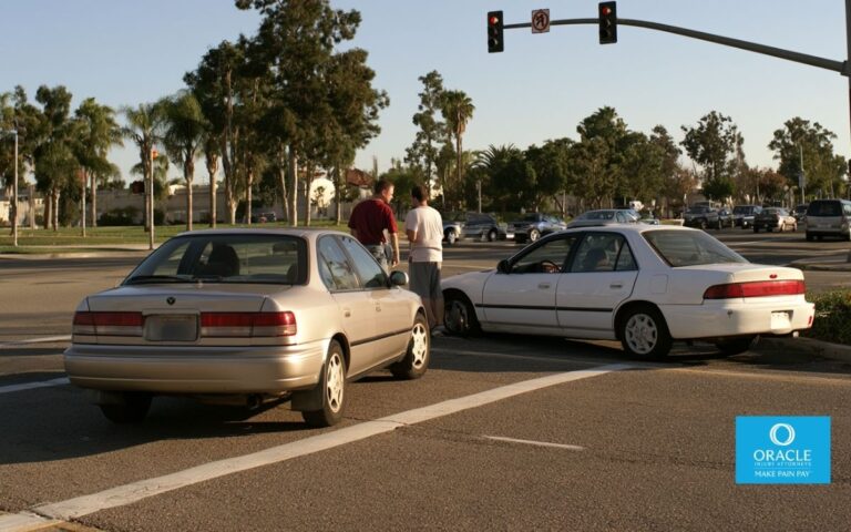 Dos coches se detuvieron tras una colisión leve en una intersección de California. Ambos conductores estaban de pie junto a sus vehículos, conversando. La imagen se ve desde la distancia; no se aprecian claramente sus rostros. Es de día. Representa el escenario de disputa sobre la culpabilidad, tema central de la publicación, sin mostrar lesiones gráficas.