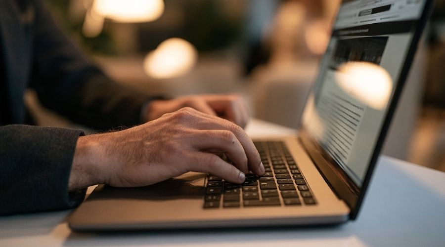 What If Your Employer Has No Workers' Comp Insurance? 2 A person's hand typing on a laptop keyboard, a state government website visible on screen, representing the online employer coverage verification lookup. No face visible, soft indoor lighting.
