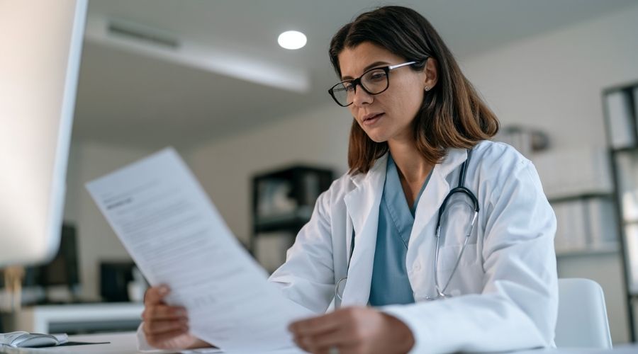 How Much Does Workers' Comp Pay in California? 2 permanent disability rating California workers comp — doctor reviewing disability assessment worksheet at a clinical desk